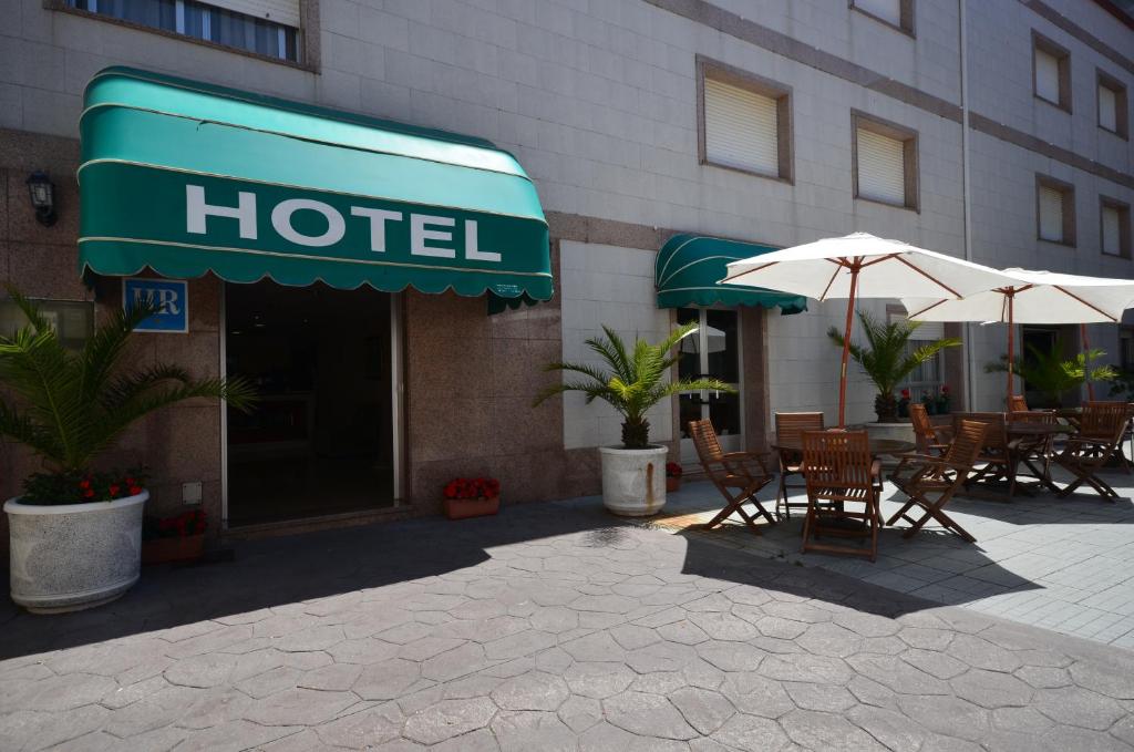 un hotel con mesas y sombrillas fuera de él en Hotel Rias Baixas en Sanxenxo