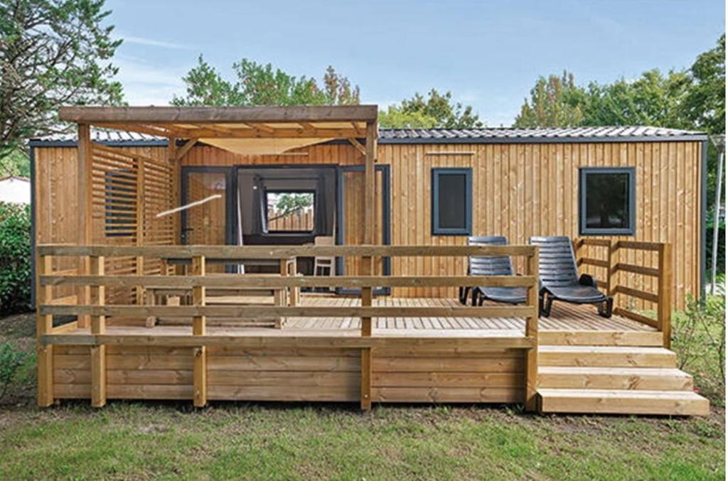 une petite maison avec une terrasse et deux chaises dans l'établissement Mobil-home Premium Mayotte - 3 Ch - 2 sdb, à Biscarrosse