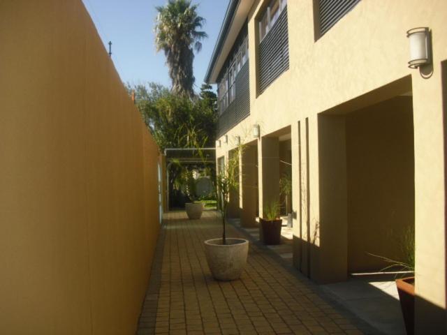 un edificio con cortile con piante in vaso accanto ad esso di The Other House - Cape Town a Città del Capo