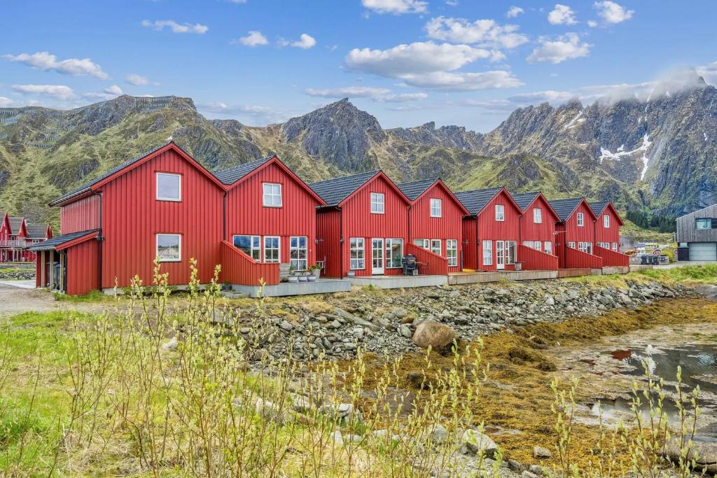 een rij rode huizen voor de bergen bij Waterfront cabin in the middle of Lofoten in Ballstad