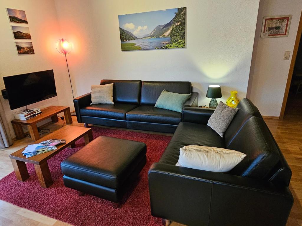 a living room with a black leather couch and a table at Jungholz Erlebnis in Jungholz