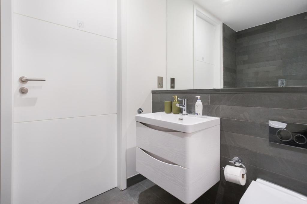 a white bathroom with a sink and a toilet at The Vale - Luxury Apartments in London