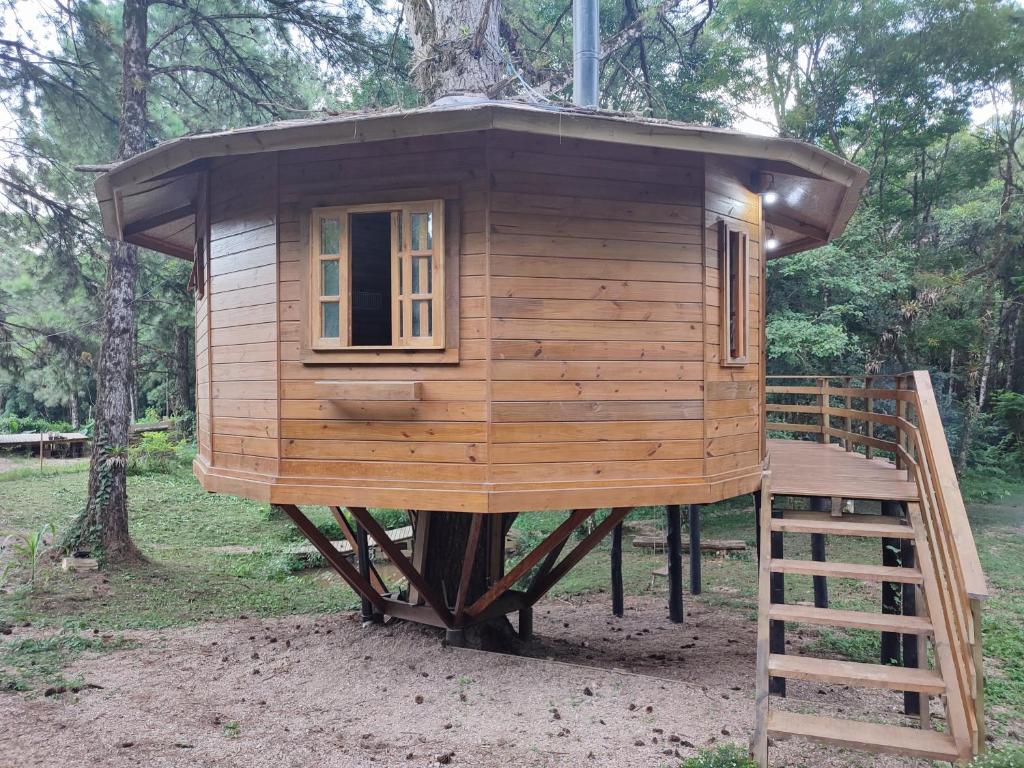 a wooden tree house with a staircase in a forest at Casa na Árvore - Chalé Quemeninho in Apiaí