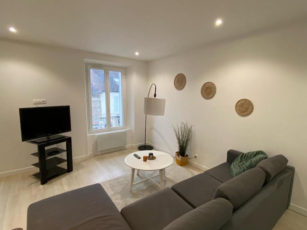 a living room with a couch and a tv at Le Grand Rambolitain in Rambouillet