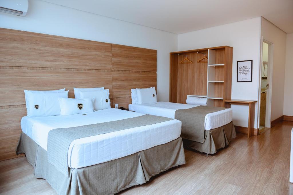 a bedroom with two beds and a book shelf at Riellis Center Hotel in Botucatu