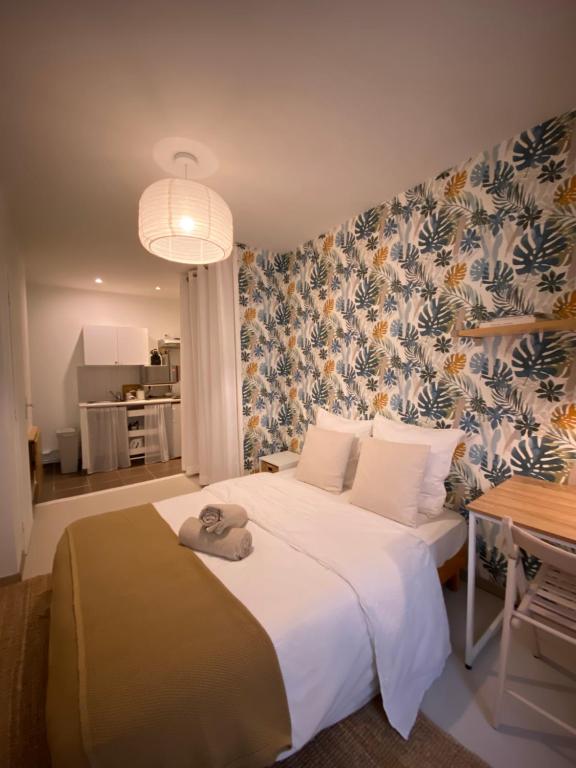 um quarto com uma grande cama branca e papel de parede floral em Joli studio centre historique et au calme (2) em Montpellier