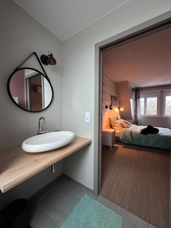 a bathroom with a sink and a bedroom with a bed at Maison d hôtes SPA Pivoine et Colibri in Domfessel