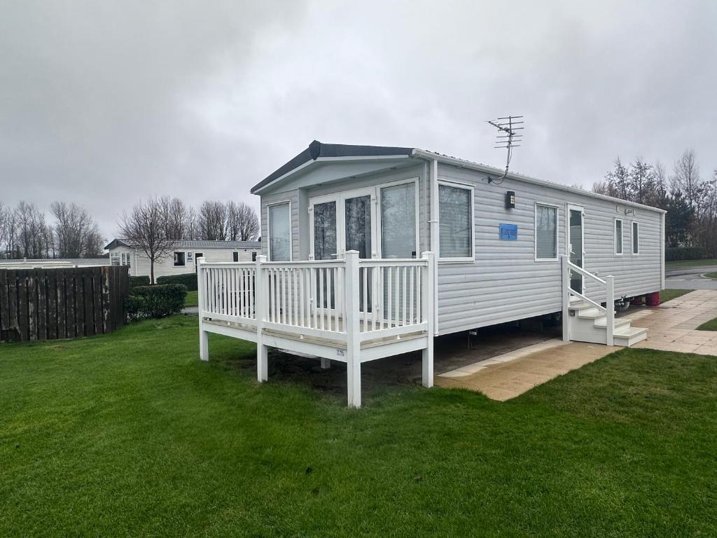 a small white house with a porch on a yard at Seton sands holiday village in Port Seton