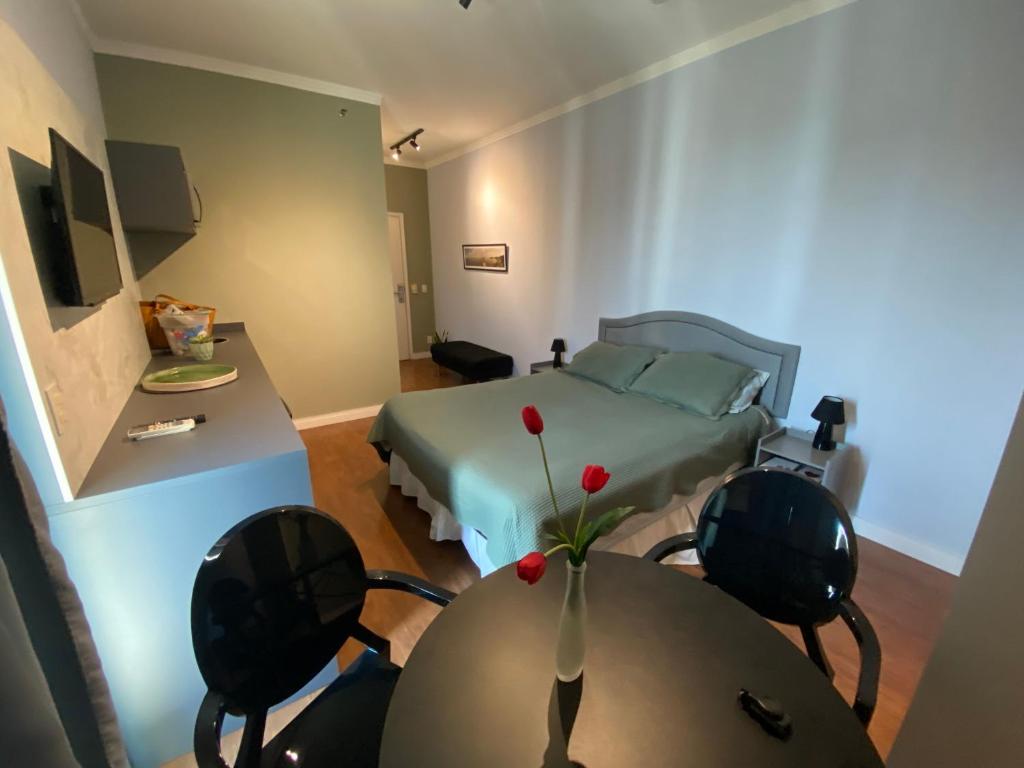 a bedroom with a bed and a table with a vase on it at Flat BOUTIQUE em frente ao metrô MOEMA in Sao Paulo