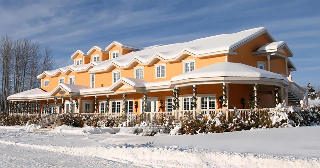 uma grande casa laranja com neve em cima em Auberge La Daïna em Baie-Saint-Paul
