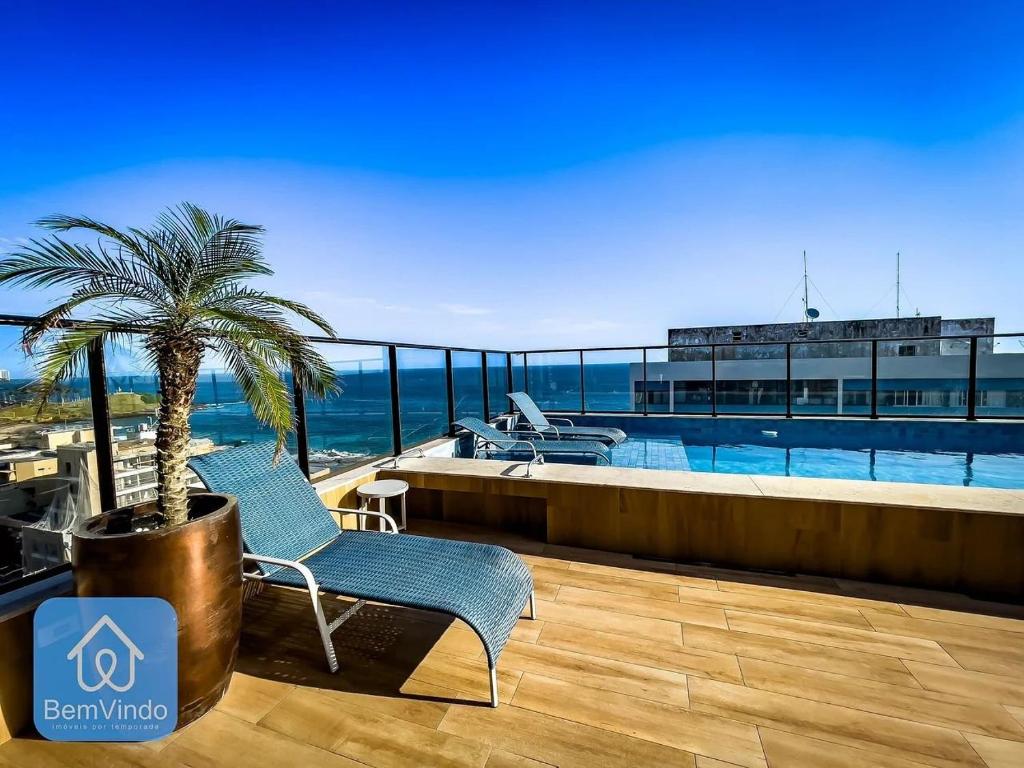 eine Terrasse mit einer Palme und einem Pool in der Unterkunft Apartamento aconchegante na Barra com vista mar in Salvador