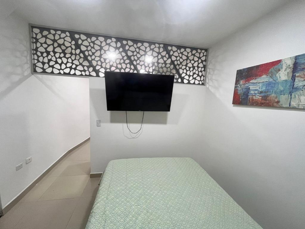 a room with a bed and a tv on a wall at Apto Amoblado Alameda Cali in Cali