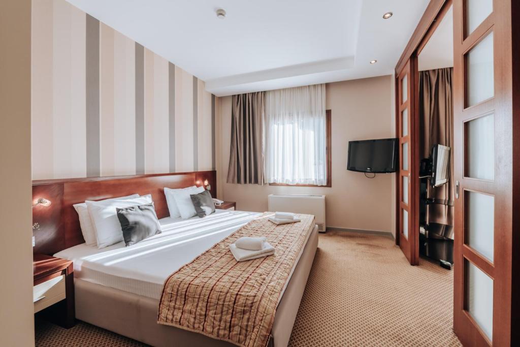 a hotel room with a large bed and a television at Apartments Del Mar in Petrovac na Moru