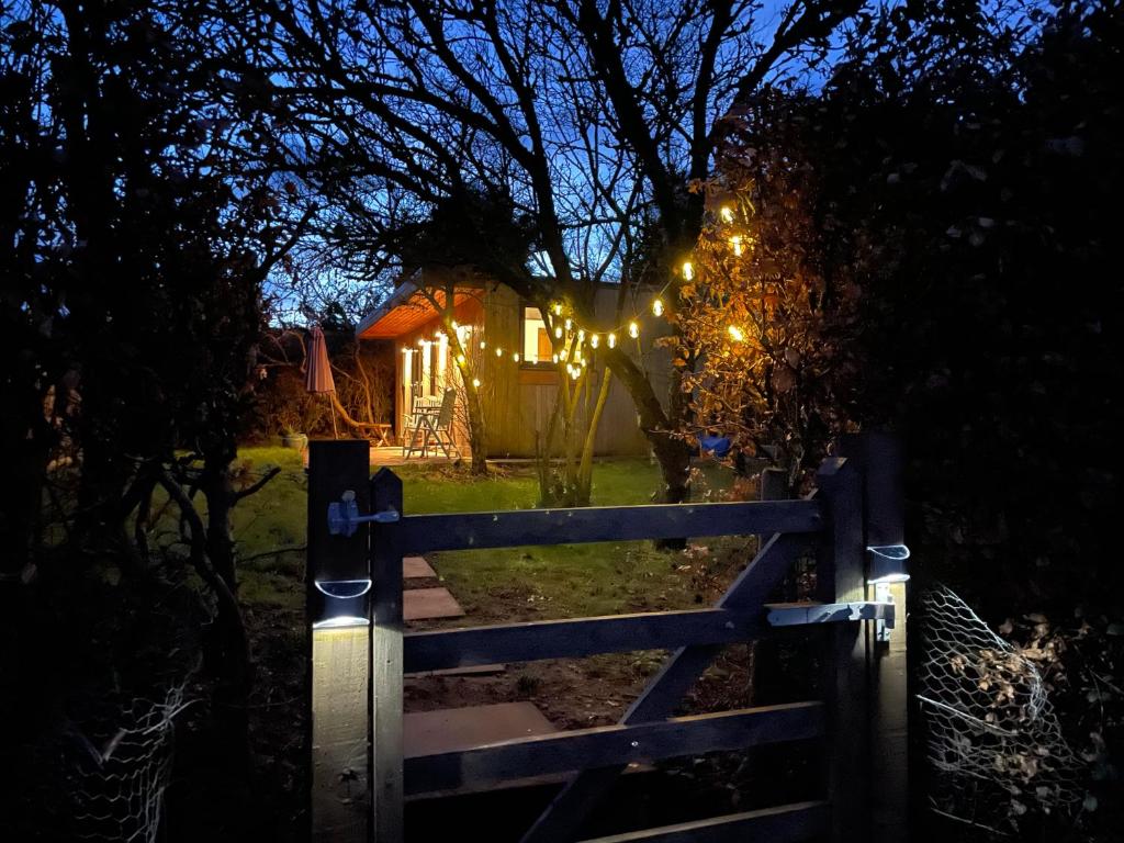 a gate leading to a house at night with lights at Cedar Cabin Holiday Let - Kinver in Stourbridge
