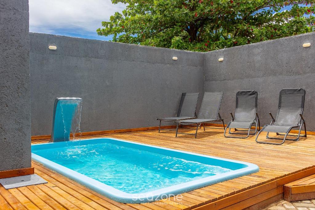 - une piscine sur une terrasse en bois entourée de chaises dans l'établissement VDA - Casas encantadoras e próximas à praia Camaragibe/AL, à Passo de Camarajibe