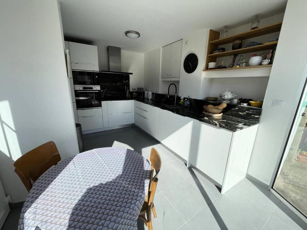 a kitchen with white cabinets and a table and a table and chairs at Résidence -pleneuf Val Andre - Maisons & Villas 604 in Pléneuf-Val-André