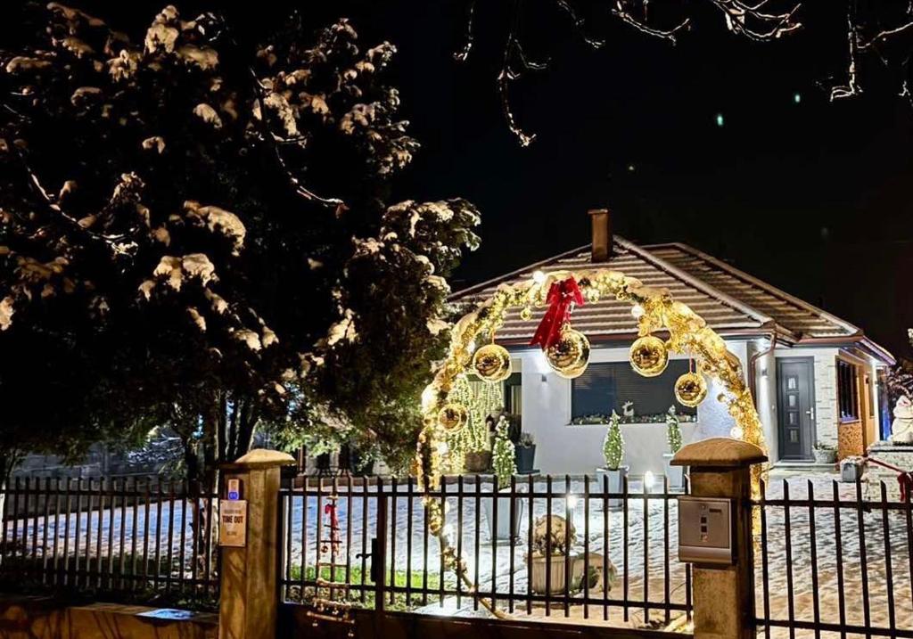 dom ozdobiony światłami świątecznymi i ogrodzeniem w obiekcie Holiday Home TimeOut Bizovac w mieście Bizovac