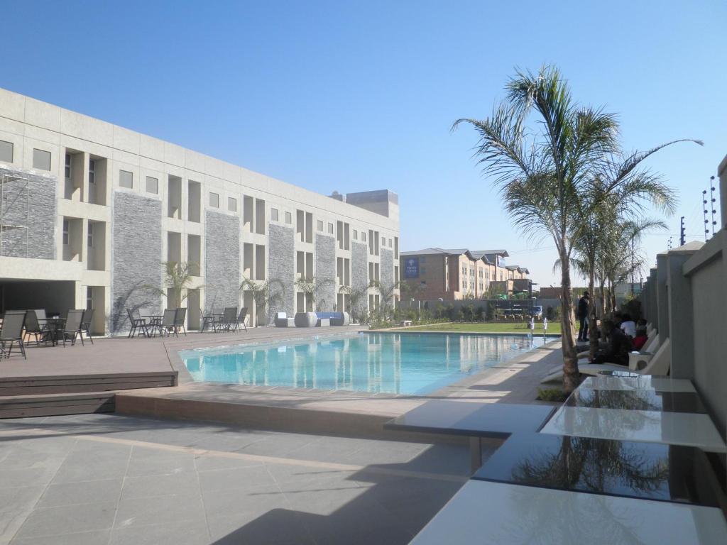 a swimming pool in front of a building at Aquarian Tide Hotel in Gaborone