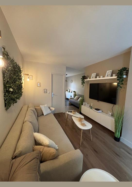 un salon avec un grand canapé et une télévision dans l'établissement Appartement Cosy avec Jardin, à Boulogne-sur-Mer