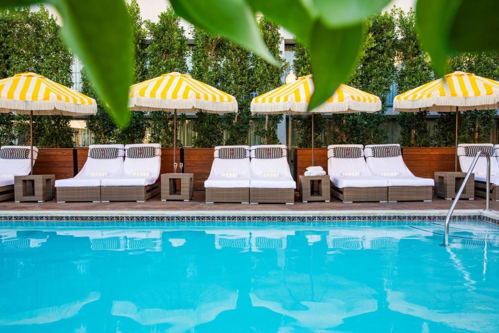 una fila de sillas y sombrillas junto a una piscina en Hotel Dena, Pasadena Los Angeles, a Tribute Portfolio Hotel, en Pasadena