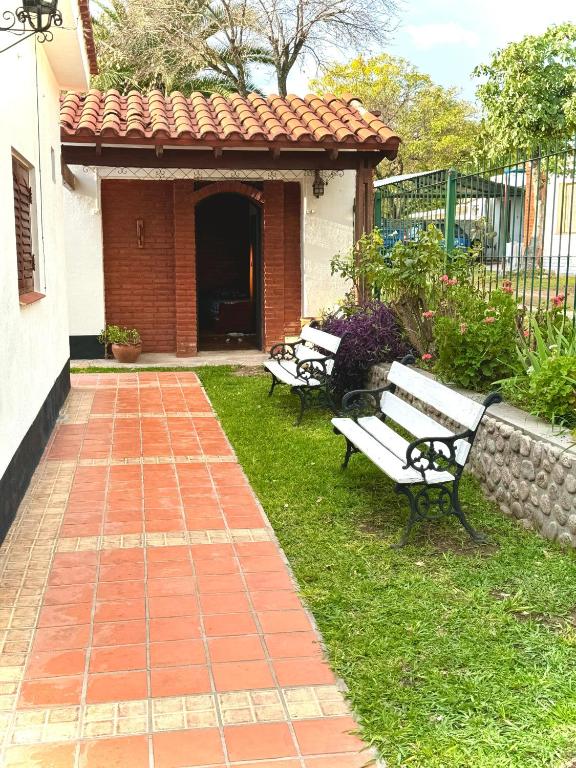 three park benches sitting in the grass near a building at Habitacion con baño privado in Mina Clavero