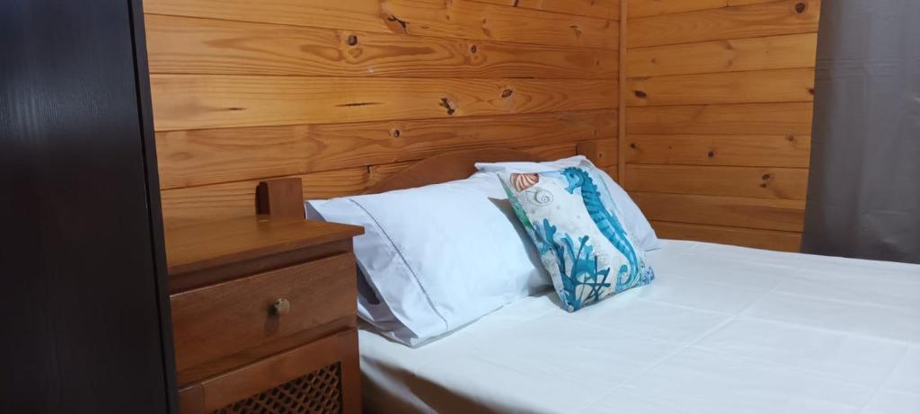 um quarto com uma cama branca e uma cabeceira em madeira em Tiny House Novas Palmeiras em Florianópolis