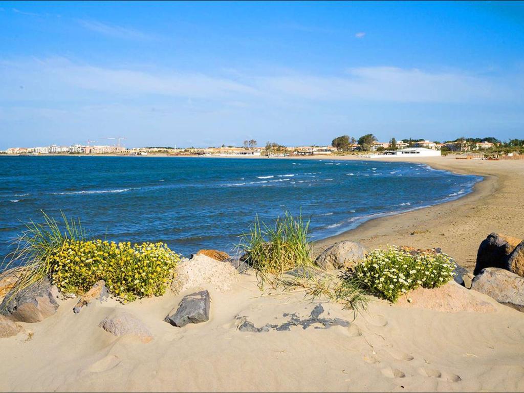 a sandy beach with rocks and the ocean at Appartement Cap d&#39;Agde, 2 pièces, 4 personnes - FR-1-749-37 in Cap d&#39;Agde