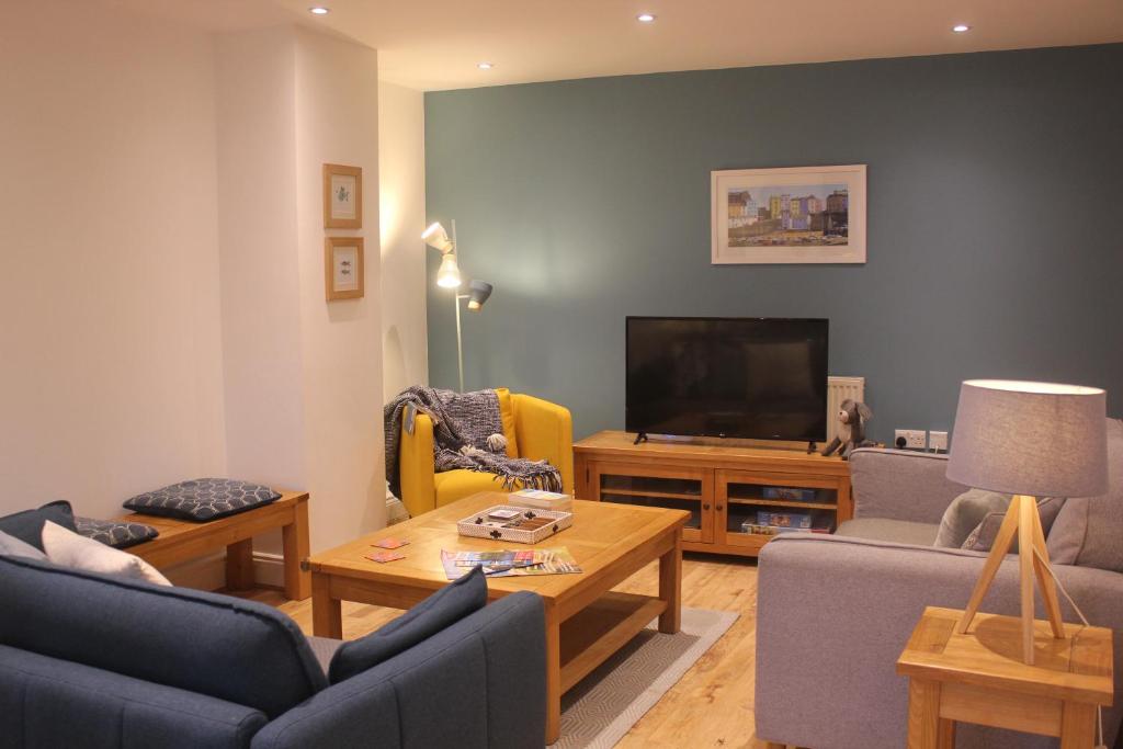 a living room with couches and a flat screen tv at Stylish flat in central Tenby & free parking in Tenby