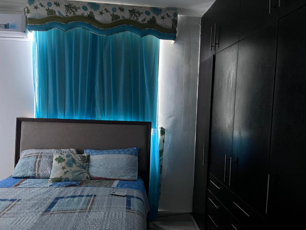 ein Schlafzimmer mit einem Bett mit einem blauen Vorhang in der Unterkunft MM VILLA in Panama-Stadt