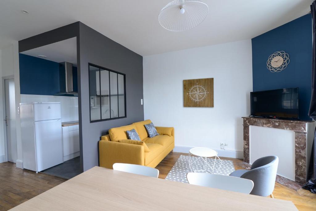 un salon avec un canapé jaune et une cuisine dans l'établissement LE PALAIS DES THERMES, à Nancy