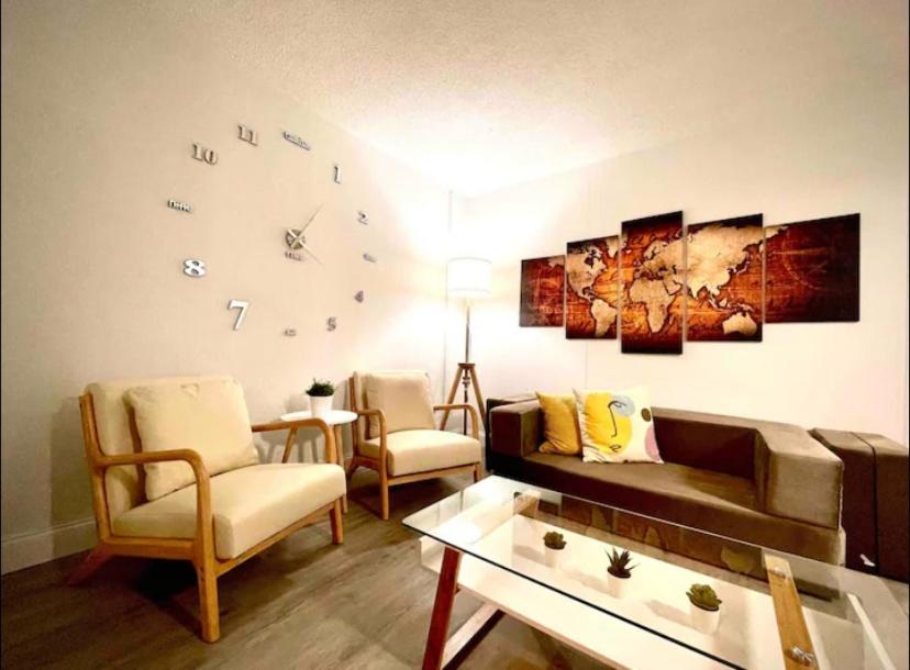 uma sala de estar com um sofá e um relógio na parede em Miami International Airport 1 em Miami
