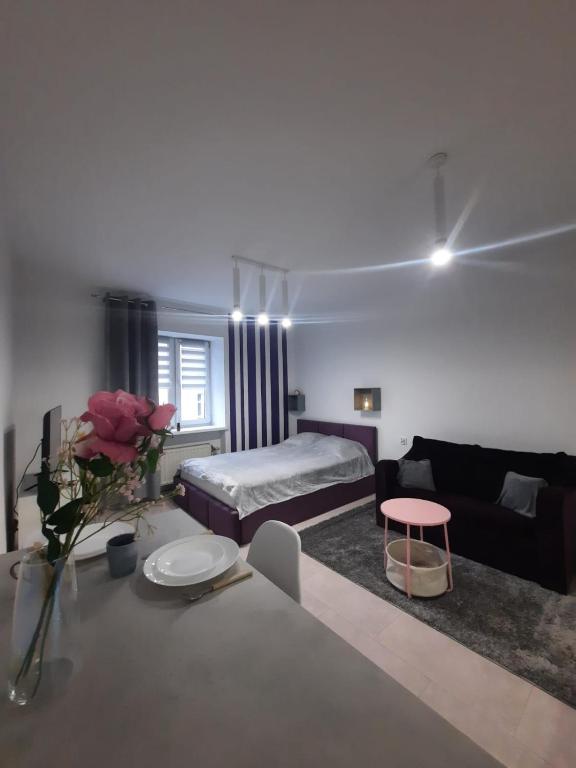 ein weißes Wohnzimmer mit einem Bett und einem Tisch in der Unterkunft Studio Violet blisko rynku in Kalisz