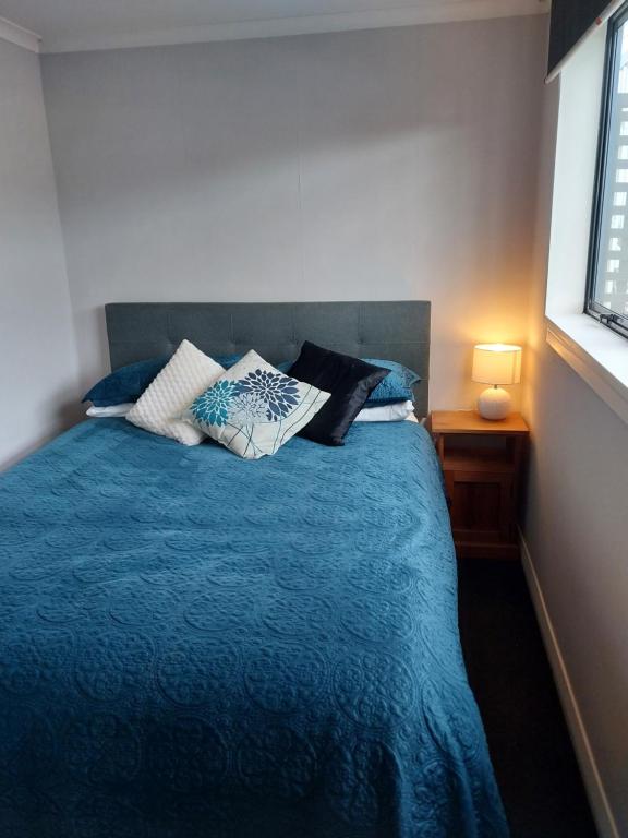 a bedroom with a blue bed with pillows on it at The Snug - Rural Hideaway in Invercargill