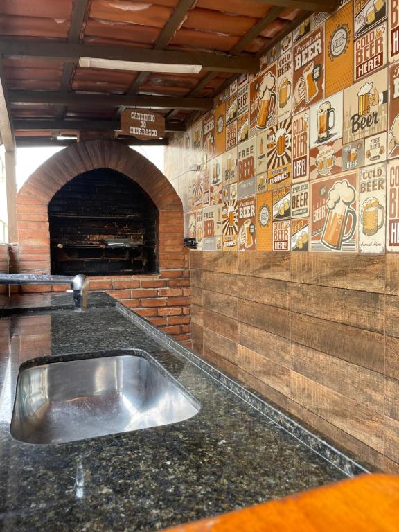 a kitchen with a stainless steel sink in front of a brick wall at Apartamento Praia do Morro com Churrasqueira, Cozinha Gourmet e Wifi in Guarapari