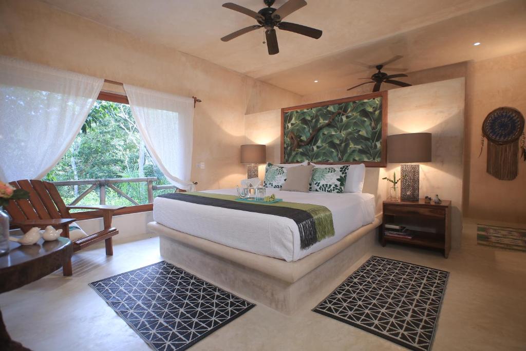 a bedroom with a bed with a fan and a window at Cachito de Cielo Luxury Jungle Lodge in Tulum