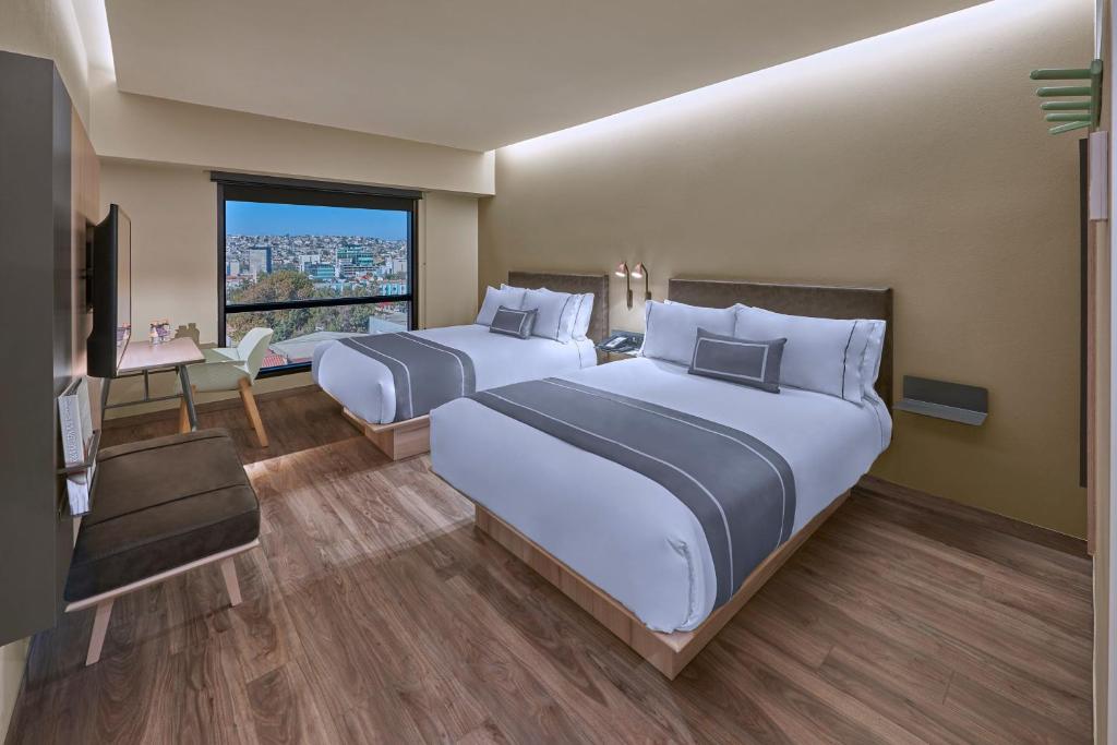 a hotel room with two beds and a television at City Express Plus by Marriott Tampico in Tampico