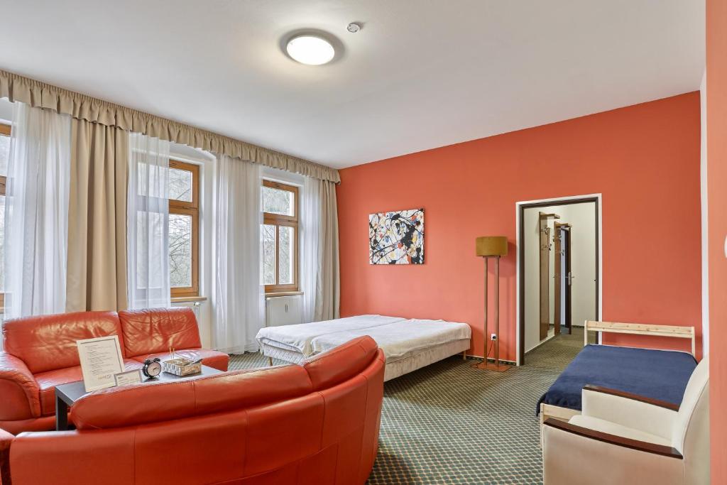 ein Schlafzimmer mit orangefarbenen Wänden und einem Bett und einem Sofa in der Unterkunft Excellent apartments in Karlovy Vary in Karlsbad