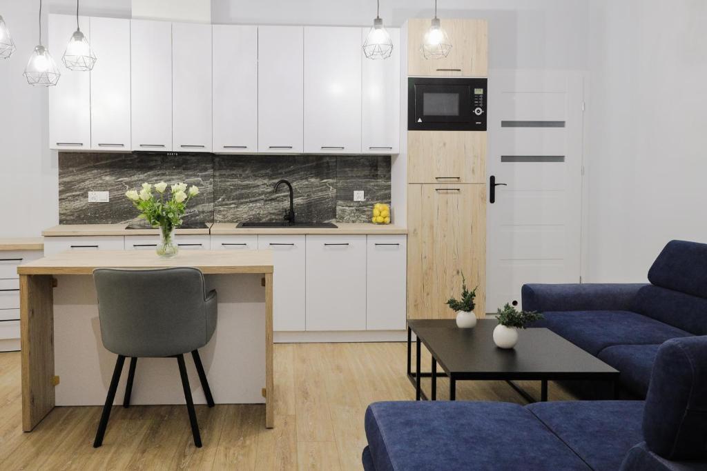 Apartamenty Różane في Laski: مطبخ وغرفة معيشة مع دواليب بيضاء وأريكة زرقاء