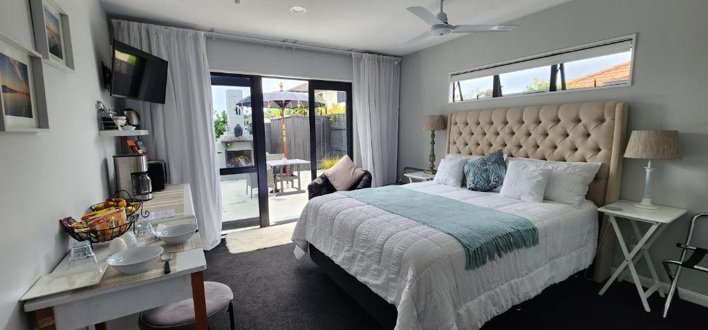 a bedroom with a large bed and a balcony at Sunkist B & B in Papamoa
