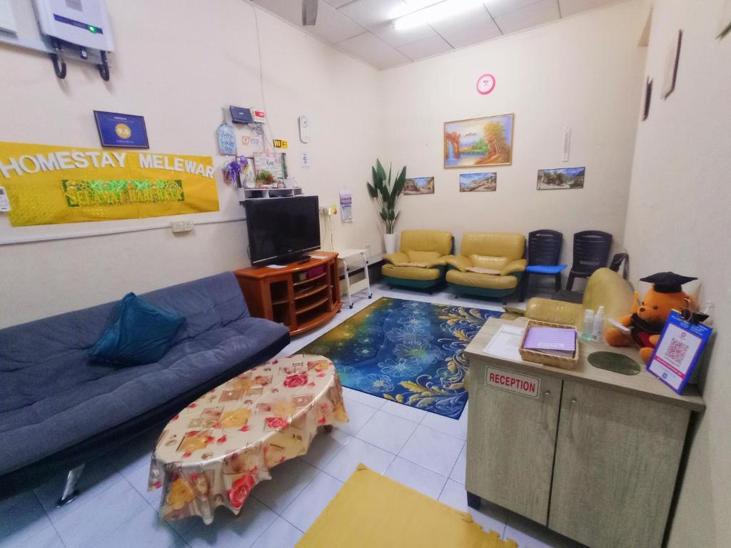 a waiting room with a blue couch and a tv at Homestay Melewar in Parit Raja