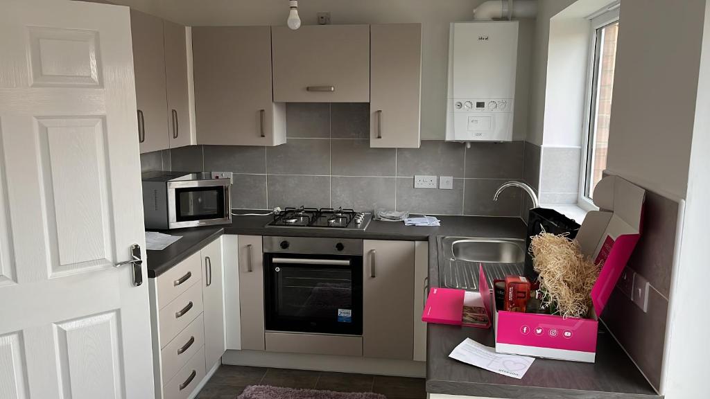 a kitchen with white cabinets and a stove top oven at Room near Teesside University in Middlesbrough