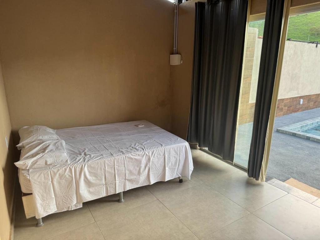 sypialnia z łóżkiem i dużym oknem w obiekcie Cantinho da Alegria w mieście Raul Soares