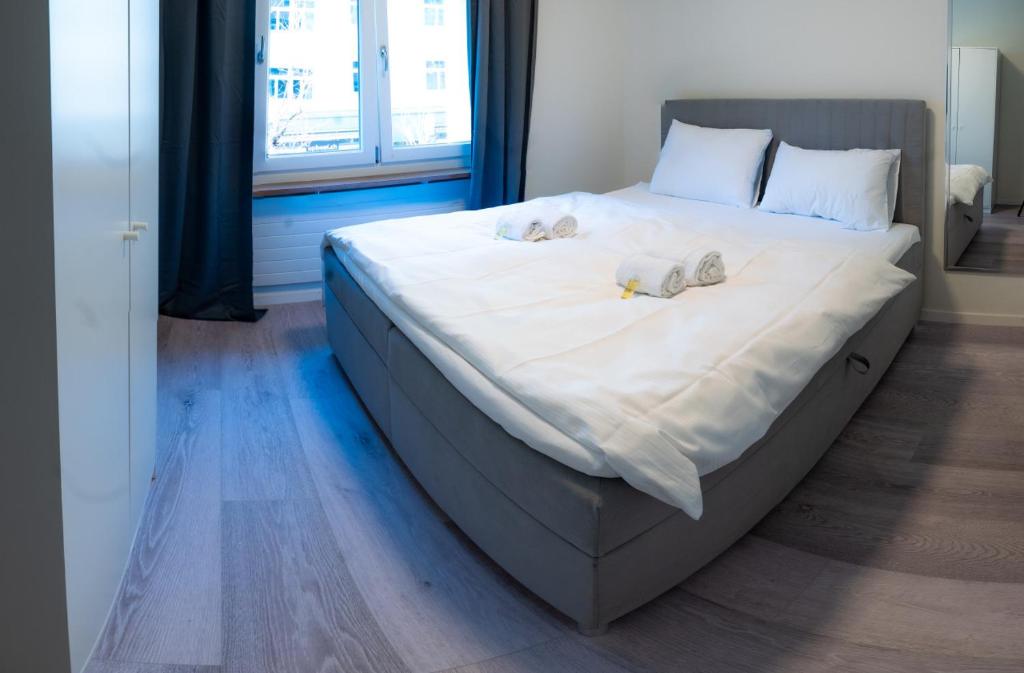 a large bed with white sheets and shoes on it at Urban Oasis with Queen Bed and View BE-13 in Zürich