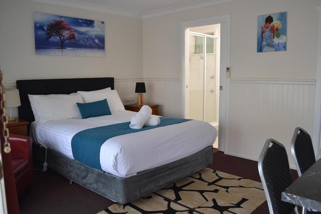 1 dormitorio con 1 cama grande, mesa y sillas en Lithgow Motor Inn en Lithgow