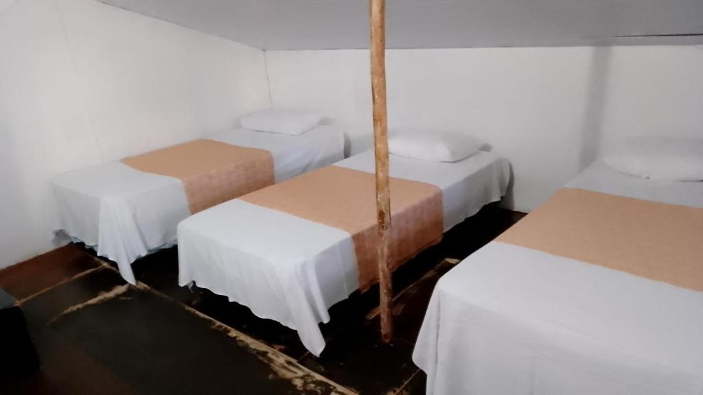 3 camas en una habitación con sábanas y cajas blancas en Hostel Nossa Sra de Lourdes en Salvador