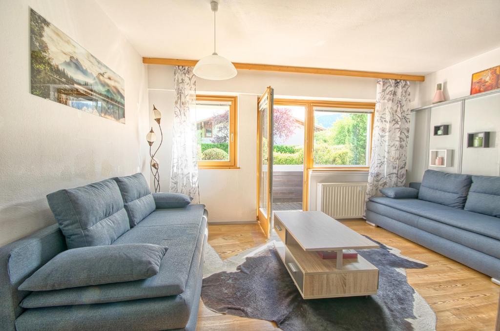 ein Wohnzimmer mit blauen Sofas und einem Tisch in der Unterkunft Apartment Valentina - by Alpen Apartments in Zell am See