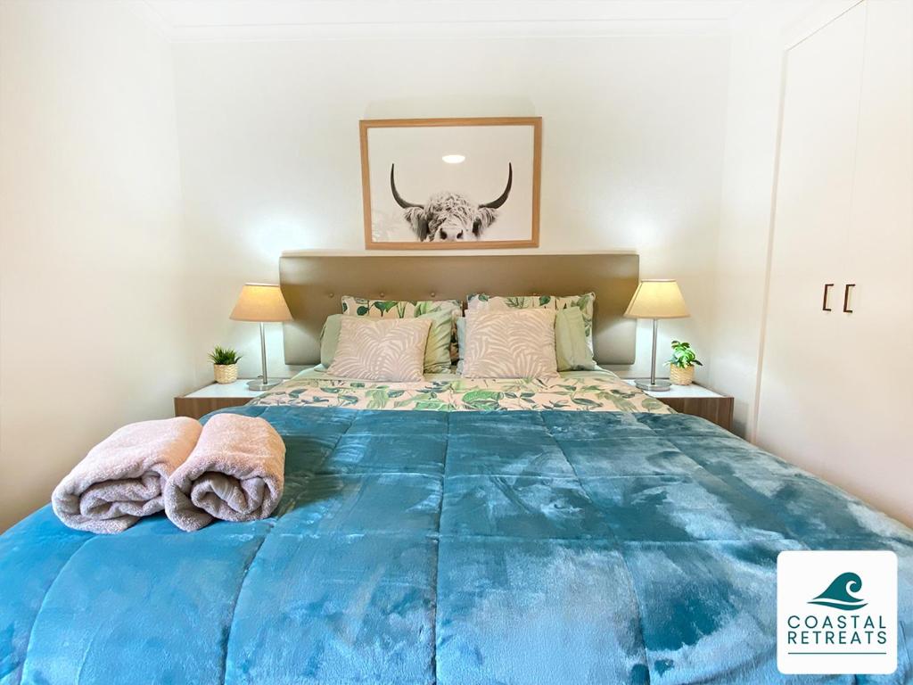 a bedroom with a large blue bed with two lamps at Woodland Retreat - Phillip Island - Ramada Resort in Cowes