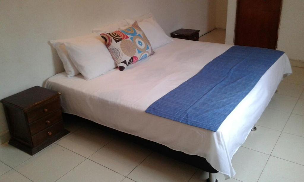 1 cama con sábanas y almohadas blancas y mesita de noche en Casa de Playa Nativo, en Cartagena de Indias