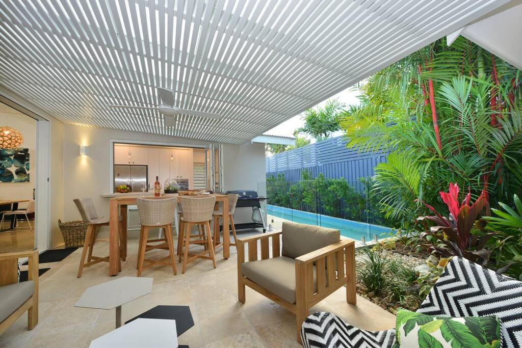 een woonkamer met een tafel en stoelen en een zwembad bij Tropical Villa on Craven Close in Port Douglas