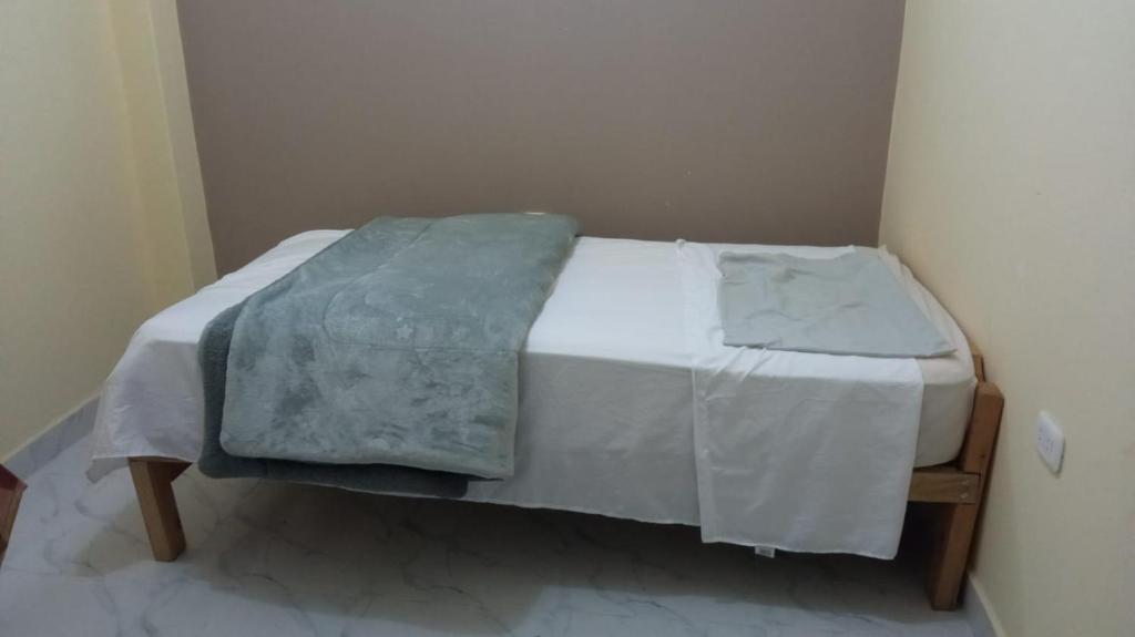ein kleines Bett mit einer Decke auf dem Zimmer in der Unterkunft habitación con cocina in Cajamarca